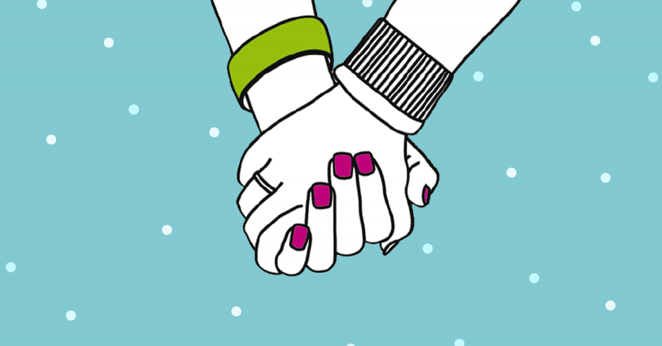 Två händer som håller i varandra när det snöar